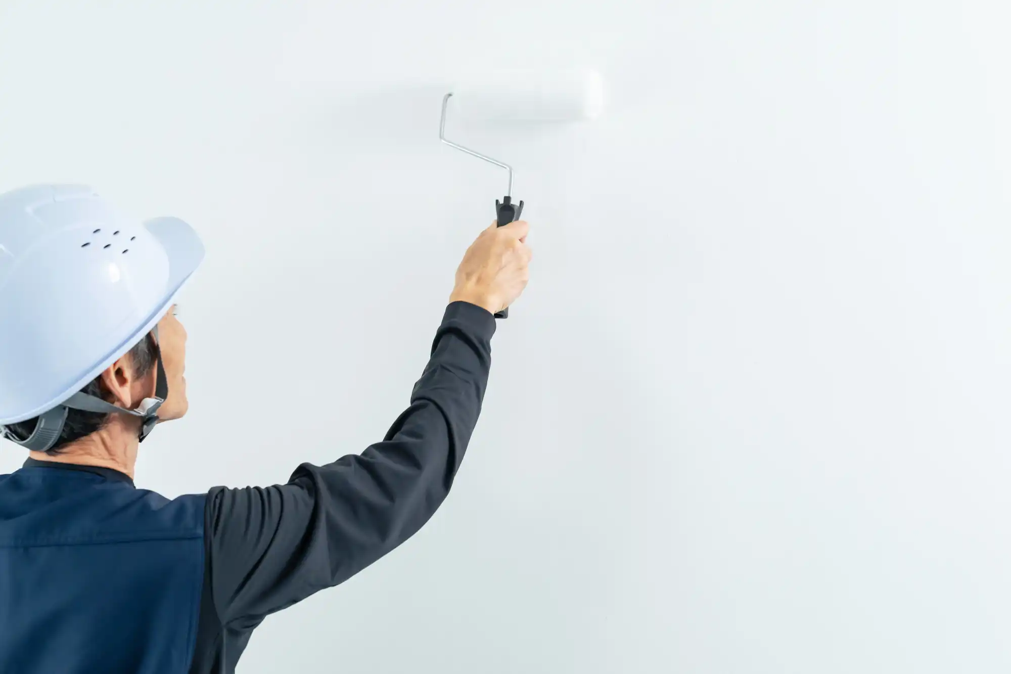 白の塗料で壁を塗っている作業員